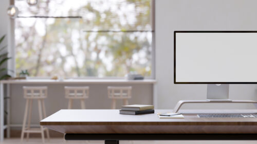 A modern workspace with a computer mockup on a desk in a modern office co-working space.